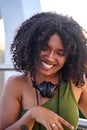 portrait of a young latina with curly hair and headphones on her neck laughing with an embarrassed face