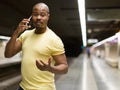 Young latino american man using phone at subway platform