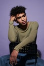 Portrait of young latino man sitting on black chair in studio. Handsome transgender male in casual Royalty Free Stock Photo