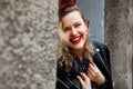 Portrait of young laughing gorgeous woman with long wavy fair hair wearing black polka-dot dress, red lipstick on lips.