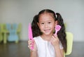 Portrait young little Asian child girl showing plastic knife and spade of frying pan in class room ready to cook learning Royalty Free Stock Photo