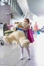 Portrait of young little girl holding her big teddy bear in airport Royalty Free Stock Photo