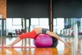 pregnant woman doing yoga bandhasana pose on fit ball in gym day side view