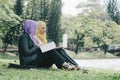 Portrait of young lovely pleasant mix ethnic woman sitting on grass at summer green park and having a discussion