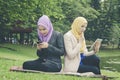 Portrait of young lovely pleasant mix ethnic woman sitting on grass at summer green park and having a discussion