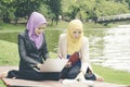 Portrait of young lovely pleasant mix ethnic woman sitting on grass at summer green park and having a discussion