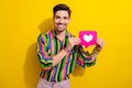 Portrait of young macho blogger hold heart button click like for his new video about picking up girls isolated on yellow