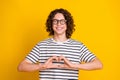 Portrait of young macho smiling guy teenager boyfriend showing affection feelings symbol heart isolated on yellow color