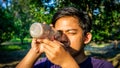 Portrait of young Malay man seeing inside a glass bottle which act as binocular