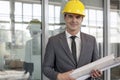 Portrait of young male architect holding rolled up blueprints in industry Royalty Free Stock Photo