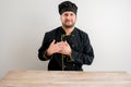 Young male chef in black uniform holds her hands on her chest near her heart Royalty Free Stock Photo