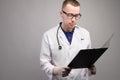 Portrait of a young male doctor in glasses with a stethoscope around his neck. In the hands of a folder, a tablet holder Royalty Free Stock Photo