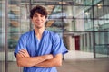 Portrait Of Young Male Doctor Wearing Scrubs Standing In Modern Hospital Building Royalty Free Stock Photo