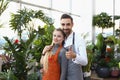 Young male and female consultants work in flower delivery shop and sale indoor plants