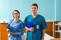 Portrait of young male and female doctor in uniform with phonendoscope on her neck holding clipboards Royalty Free Stock Photo