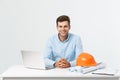 Portrait of young male interior designer or engineer smiling while sitting on his office table.