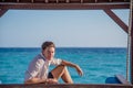 Portrait of young male model in expensive shirt sitting on the swing at the tropical island luxury resort Royalty Free Stock Photo