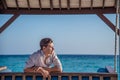 Portrait of young male model posing in expensive shirt sitting on the swing at the tropical island luxury resort Royalty Free Stock Photo