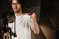 Portrait of young male musician in headphones sensually singing recording song in modern studio Royalty Free Stock Photo