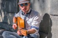 Portrait of young male street musician playing guitar on a city sidewalk. Freedom, music and art concept. Horizontal image Royalty Free Stock Photo