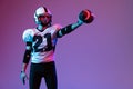 Portrait of young man, american football player in uniform training catching ball with one hand isolated over purple Royalty Free Stock Photo