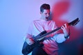 Portrait of young man artist singing, screaming, playing electric guitar Hobby, music concept. Rock Star The guy in neon plays the Royalty Free Stock Photo