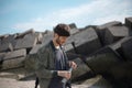 Portrait of young man with backpack, using reusable steel thermo water bottle, outdoor on background of square stones.