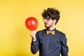 Portrait of a young man with balloon in a studio on a yellow background. Royalty Free Stock Photo