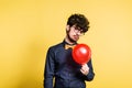 Portrait of a young man with balloon in a studio on a yellow background. Royalty Free Stock Photo