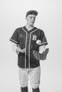 Portrait of young man, baseball player in uniform posing with ball and glove. Black and white photography Royalty Free Stock Photo