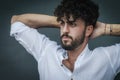 Portrait of a young man with beard and curly hair, who relaxes by stretching his back with his hands behind his neck Royalty Free Stock Photo