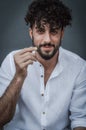 Portrait of a young man with a beard and curly hair, who is smiling while with his hand raised he is gesturing