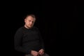 Portrait of a young man with a beard sitting on a chair. Dark background. A slightly overweight man with a large build. Interview