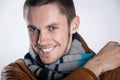 Portrait of young man in brown jacket with striped scarf over gray background. Close-up.