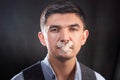 Portrait of a young man in a business suit and glasses with glued lips. The concept of silence, mystery, secret Royalty Free Stock Photo