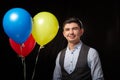 Portrait of a young man in a business suit and wigh with balloons. Positive guy posing in the studio Royalty Free Stock Photo