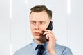 Portrait of young man businessman dressed in blue shirt and tie, talking on the mobile phone Royalty Free Stock Photo