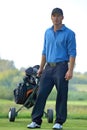 Portrait of young man carrying trolley with golf bag Royalty Free Stock Photo
