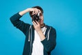 Portrait of young man in casual clothes holding taking pictures on retro vintage photo camera isolated on blue wall Royalty Free Stock Photo