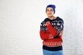 Portrait of young man in Christmas sweater and hat near white brick wall. Royalty Free Stock Photo