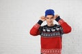 Portrait of young man in Christmas  and hat near white brick wall. Space for text Royalty Free Stock Photo