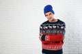 Portrait of young man in Christmas sweater and hat near white brick wall. Space for Royalty Free Stock Photo