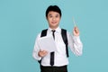 Portrait of young man in college uniform and tie holding notebook and pencil isolated on blue background. concept of thinking Royalty Free Stock Photo