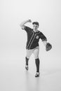 Portrait of young man, concentrated baseball player, pitcher in a glove serving ball. Black and white photography Royalty Free Stock Photo