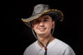 Portrait of a young man in a cowboy hat. Positive guy posing in the studio with black background Royalty Free Stock Photo