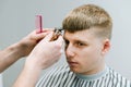 Portrait of a young man cutting hair in a barber shop with a serious face,close-up of a hairdresser with a trimmer cut client`s Royalty Free Stock Photo