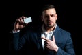 Portrait of a young man dressed in suit pointing finger at a credit card isolated over black background. Businessman Royalty Free Stock Photo