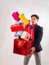 Portrait of young man dropping pile of presents and gifts