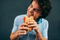 Portrait of young man eating a cheeseburger has pleasant expression. Happy man in a fast food restaurant eating a hamburger Royalty Free Stock Photo