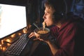 Portrait of a young man eating a noodle soup and enjoying a computer at night at home Royalty Free Stock Photo